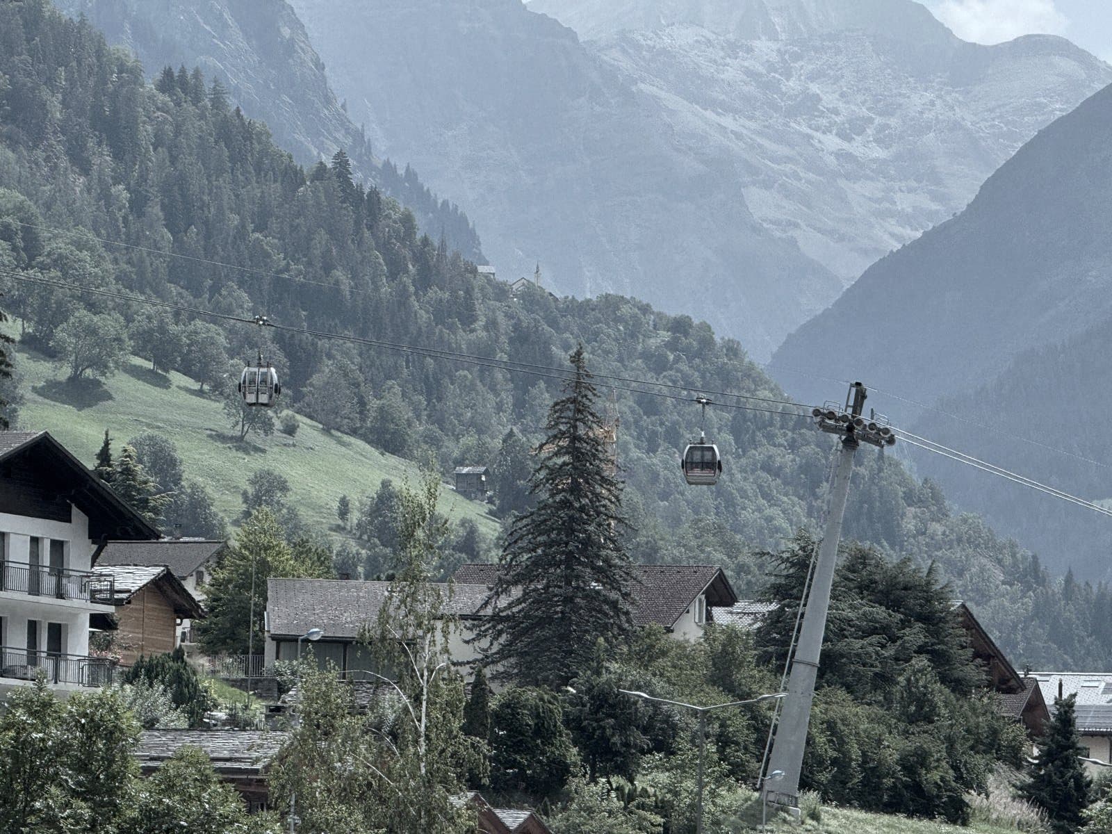 La télécabine du Châble au-dessus des toits, deux cabines croisées sur fond de versants boisés.